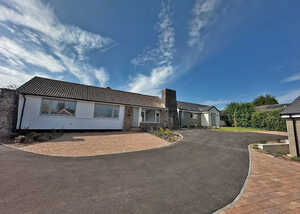 A single-story house with a circular driveway and a blue sky in the background.