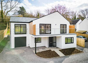 Modern two-story white house with large windows and a front porch, set in a green landscape.