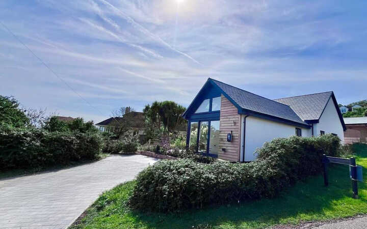 A modern house surrounded by greenery and a clear blue sky.
