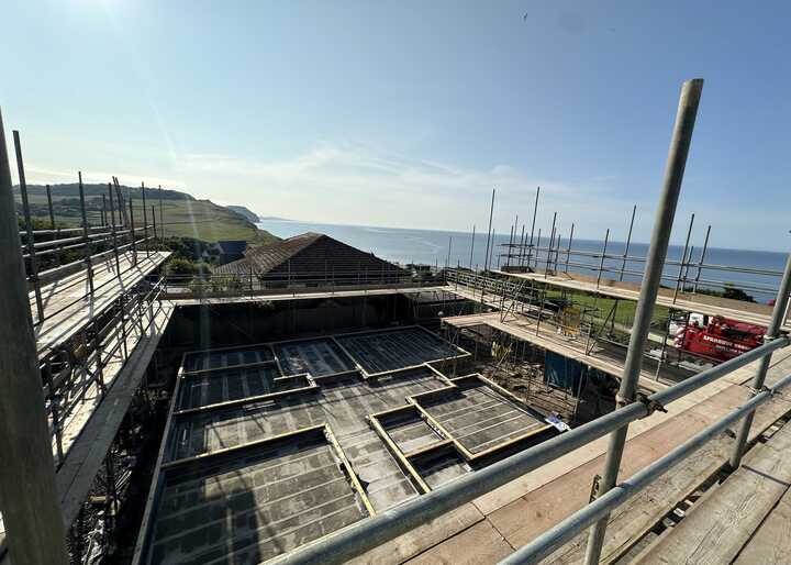 Construction site overlooking the sea with scaffolding and unfinished structures.