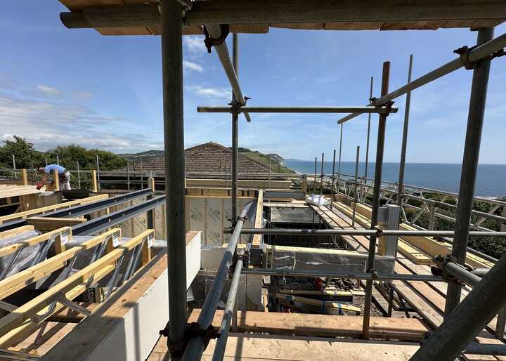 Construction site with scaffolding overlooking a coastal view and blue sky.