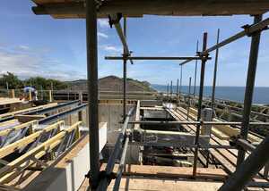 Construction site with scaffolding overlooking a coastal view and blue sky.