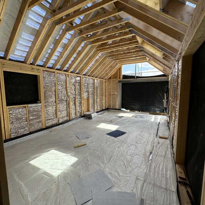 Interior of a partially constructed room with exposed wooden beams and flooring materials.