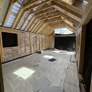 Interior of a partially constructed room with exposed wooden beams and flooring materials.
